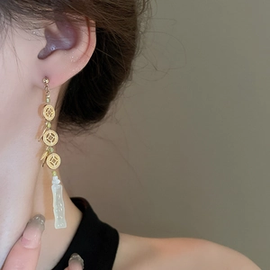 Close-up of Chinese style tassel earrings with gold coins and green bamboo pendant