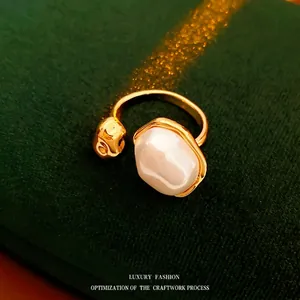 Minimalist gold plated open ring featuring a baroque pearl and lava textured metallic ball