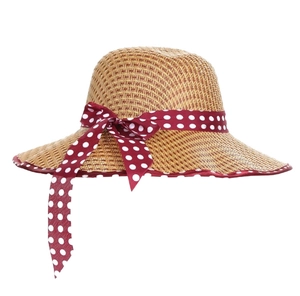 Close-up of woven straw sun hat featuring a red polka dot ribbon and bow detail