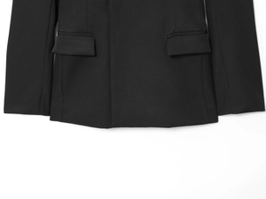 Detail shot of black oversized blazer featuring classic flap pockets and textured fabric