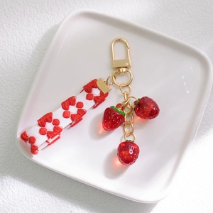 Close-up of strawberry pendants with floral ribbon and gold metal keychain clip
