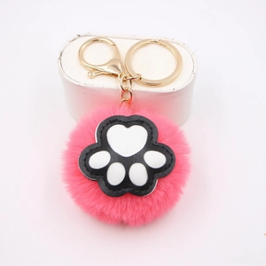 Close-up of pink faux fur pompom keychain with black and white cat paw detail