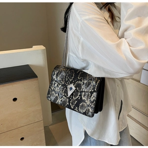 Detail of snake skin pattern texture and diamond metal clasp on the chain crossbody bag