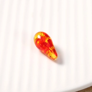 Detailed close-up of a teardrop-shaped amber resin bead with colorful gradient finish