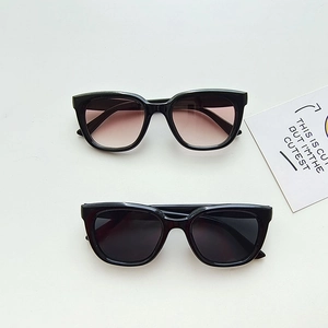 Detail view of girls black frame sunglasses with grey and brown gradient lenses
