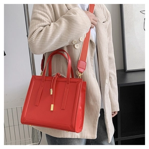 Detail of red square crossbody bag with wide fabric strap and golden metal hardware details