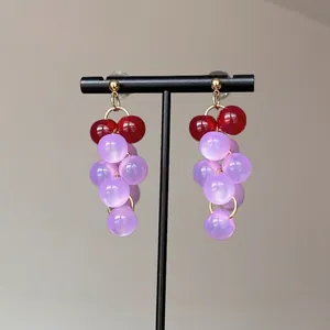 Détail de boucles d'oreilles grappe de raisin créatives avec perles lilas et rouges