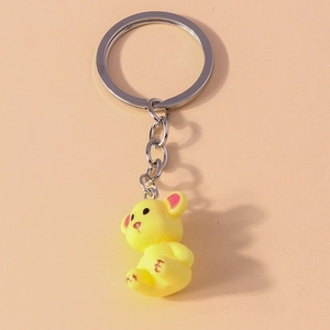 Detail of yellow resin bear keychain with red X stitch paws on peach background