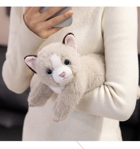 Close-up of soft plush Persian cat toy with blue eyes held against a white sweater