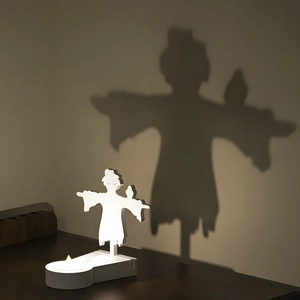 Detailed view of scarecrow projection candle holder casting a large shadow on wall