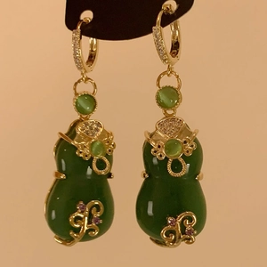Macro detail of Chinese gourd drop earrings featuring gold plating and green glass stones