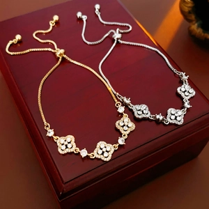 Macro detail of gold and silver four-leaf clover bracelets with adjustable sliding clasps