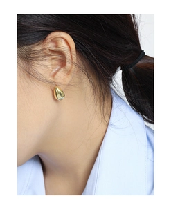 Close-up of a model wearing polished gold teardrop stud earrings in a minimalist style