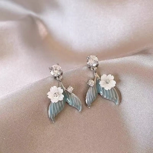Detail of fishtail earrings with blue gradient zircon and delicate white resin flowers