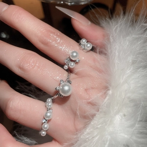 Close-up of a zircon pearl cat ring with silver finish on model hand with feathers