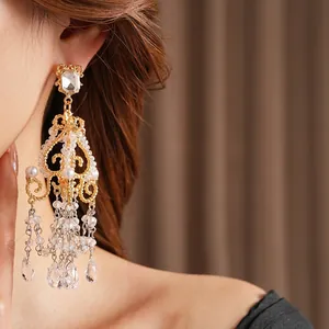 Luxurious gold chandelier earrings with white pearls and crystals worn by a model