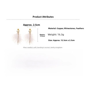 Detail of white feather drop earrings with golden bow and orange heart pendant charm