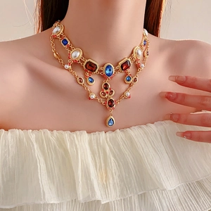 Detail of vintage layered necklace with red and blue gems plus white pearls on gold chain