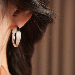 Minimalist silver hoop earring worn by a model, showing elegant and polished design details