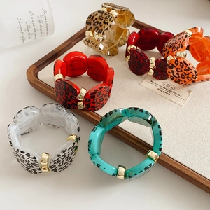 Detail of colorful leopard print acrylic bangles with gold accents on a jewelry tray