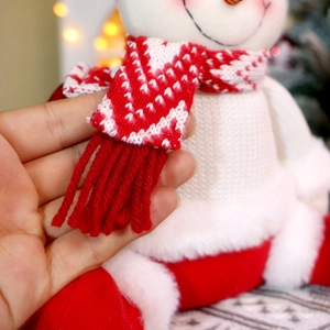 Detailansicht einer Schneemann-Puppe mit rotem Strickschal und weichem weißem Plüschgewebe