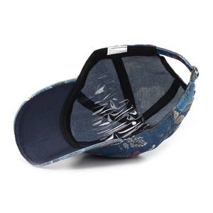 Detail of floral embroidery on denim baseball cap with adjustable metal buckle back