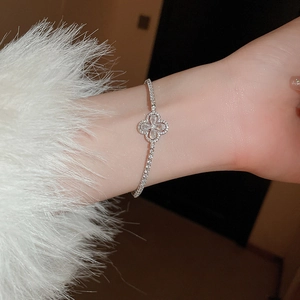 Gros plan d'un bracelet trèfle argenté avec des zircons porté sur un poignet