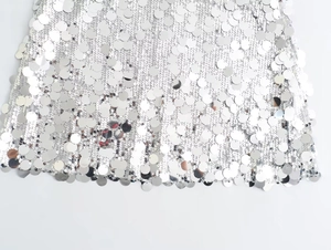 Close-up of sparkling silver sequins and mesh fabric on a stylish party mini dress