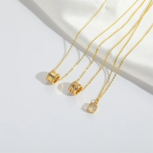 Close-up of golden necklaces with zircon cylinder pendants on white silk background