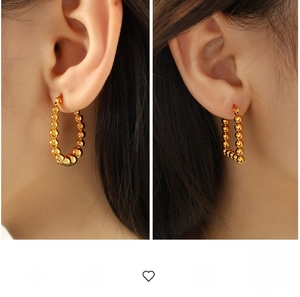 Detailed view of geometric beaded gold earrings in circular and V-shape styles on model