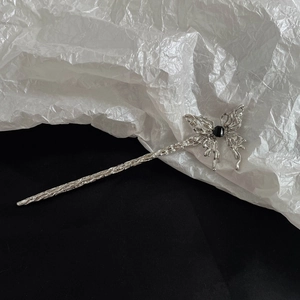 Macro detail of silver metal butterfly hair pin with black gemstone and textured finish