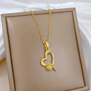 Detail of gold heart pendant with sparkling crystals on white silk in jewelry box