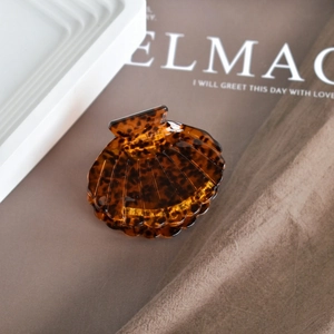 Detailed close-up of shell-shaped tortoiseshell acetate hair claw with glossy finish