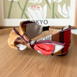 Detail of color-block satin knotted headband on a wooden tray with geometric patterns