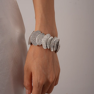 Detail of silver pleated irregular geometric metal bracelet on model's wrist