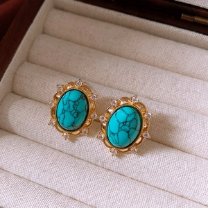 Macro shot of vintage gold earrings with oval turquoise center and zircon flower halo