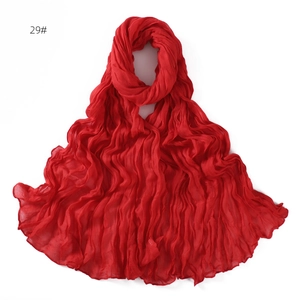 Detail of bright red pleated cotton linen scarf with soft breathable wavy texture folds