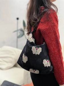Detail of vintage jacquard shoulder bag with butterfly patterns and red bead accents
