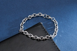 Polished silver stainless steel link chain bracelet displayed on a black leather surface