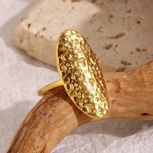 Detailed close-up of 18K gold plated ring with hammered texture on oval metal surface