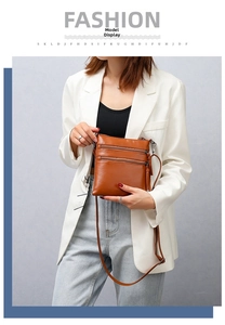 Detail of brown leather crossbody bag with three parallel zipper pockets for phone storage