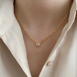 Minimalist gold necklace with a rectangular clear stone pendant shown on a model