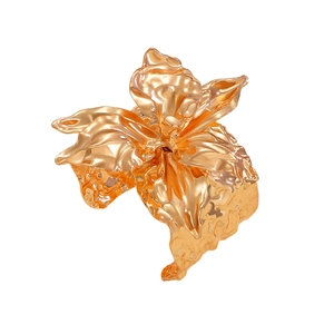 Dettaglio macro di un ornamento a fiore dorato con petali increspati e finitura lucida