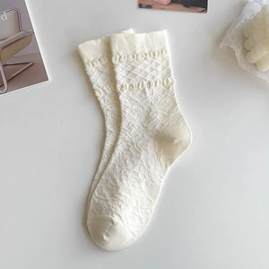 Detail of beige JK style calf socks featuring knitted floral relief and ribbed cuffs