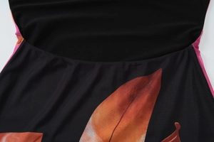 Detailaufnahme von schwarzem Netzstoff mit orangefarbenem Blattmuster und runden Nähten