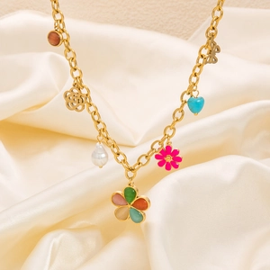 Detail of gold chain necklace with colorful flower, butterfly and heart pendants on silk