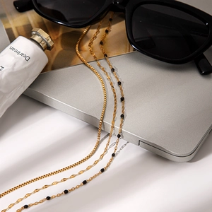 Close-up of triple-layered gold stainless steel necklace with delicate black beads and chains