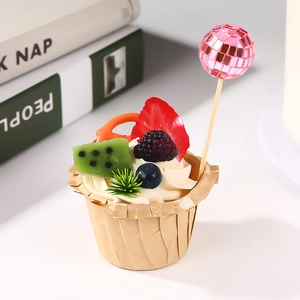 Pink disco ball cake topper on a fruit-decorated cupcake with clean white background