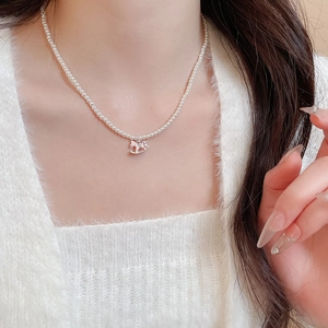Close-up of elegant pearl necklace with rocking horse pendant on white knit sweater