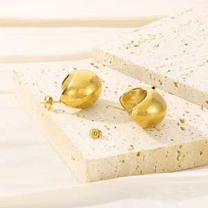 Macro detail of polished 18K gold plated hollow semi-circle earrings on a white stone base